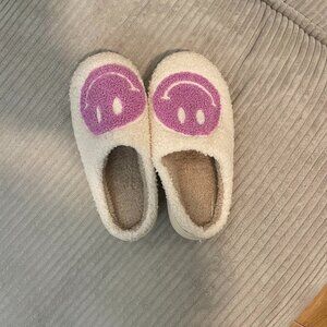 Fluffy white slippers with purple smiley faces